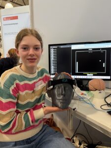 Foto: So hat man sich das Projekt vorzustellen. Das Bild zeigt Klara mit dem Headset, im Hintergrund sieht man auf dem Monitor das Pong-Spiel.